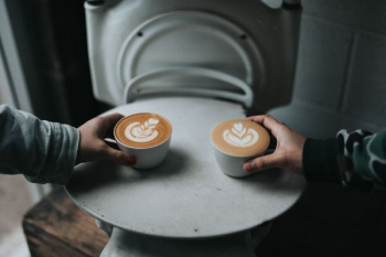two person holding cappuccino coffee cups two person holding cappuccino coffee cups