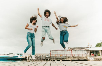 two women and one man jumping at daytime two women and one man jumping at daytime