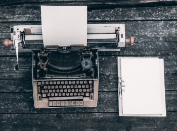 type writer beside clipboard on wooden surface type writer beside clipboard on wooden surface