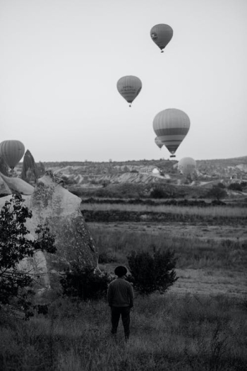 Unrecognizable Man Observing Balloon Competition Over Prairie · Free Stock Photo