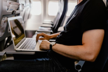 Unrecognizable man with notebook sitting inside an airplane Unrecognizable man with notebook sitting inside an airplane