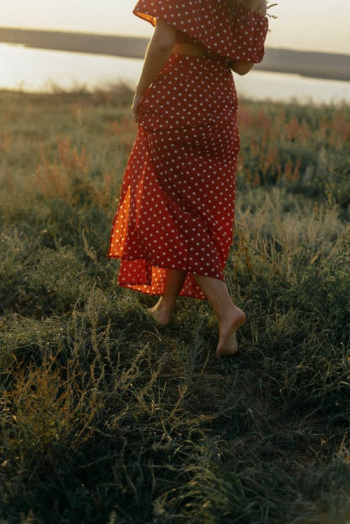 Unrecognizable Woman in Red Summer Dress Walking Barefoot in Meadow · Free Stock Photo