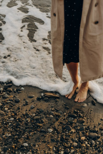 Unrecognizable Woman Standing Dressed and Barefoot on Beach at Seashore · Free Stock Photo