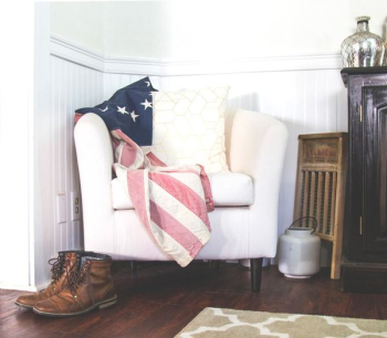US flag and white throw pillow on white fabric sofa chair in room