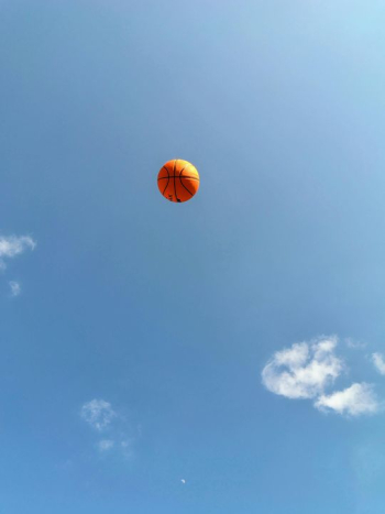 Vibrant Orange Balloon Floating in Clear Blue Sky Vibrant Orange Balloon Floating in Clear Blue Sky