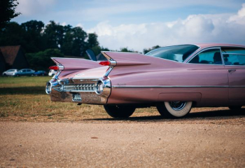 vintage pink muscle car parked near field of grass vintage pink muscle car parked near field of grass