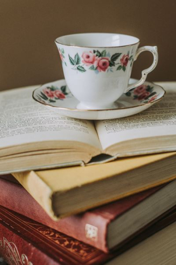 white-and-pink teacup on top of opened book white-and-pink teacup on top of opened book