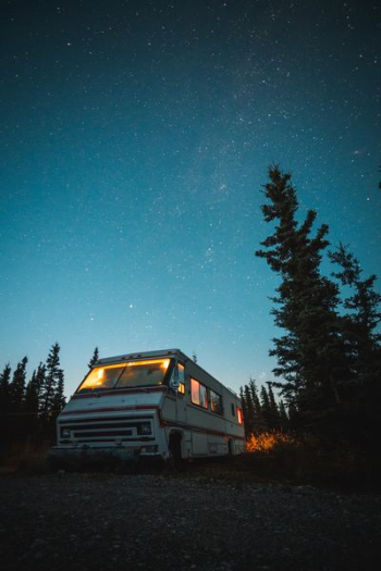 white and red RV beside trees