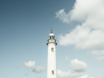 white lighthouse under white cumulus clouds