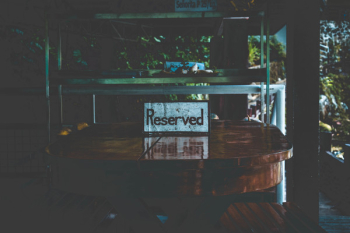 White Reserved Sign on Brown Wooden Table White Reserved Sign on Brown Wooden Table