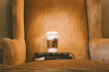 white Starbuck plastic cup on brown fabric armchair white Starbuck plastic cup on brown fabric armchair