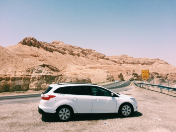 White Suv on Dirt Road Near Rock Formation