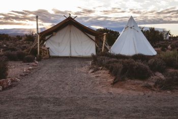 white tipi tent surrounded by grass white tipi tent surrounded by grass