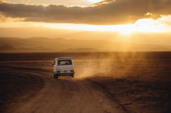 white vehicle traveling desert land field during sunset white vehicle traveling desert land field during sunset