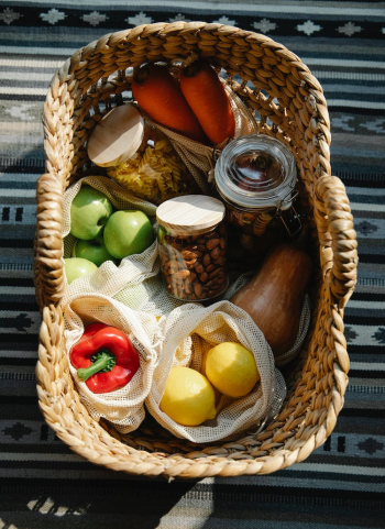 Wicker basket with vegetables and products placed on table in sunny day Wicker basket with vegetables and products placed on table in sunny day