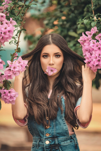 Woman Biting Pink Flower While Holding Her Hair Woman Biting Pink Flower While Holding Her Hair