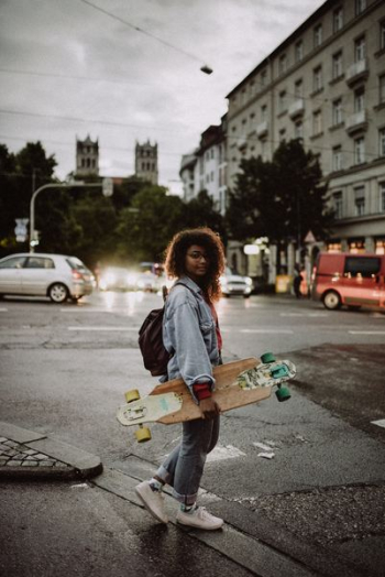 woman carrying brown longboard