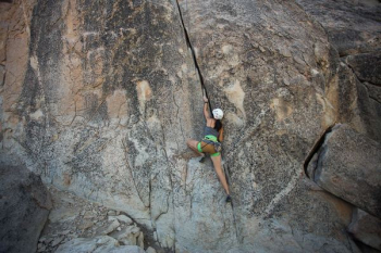woman climbing on rock cliff during daytime woman climbing on rock cliff during daytime