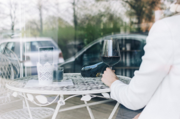 Woman drinking red wine behind a window Woman drinking red wine behind a window