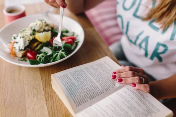 Woman eating breakfast and reading a book Woman eating breakfast and reading a book