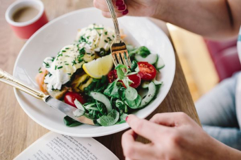Woman eating breakfast and reading a book Woman eating breakfast and reading a book