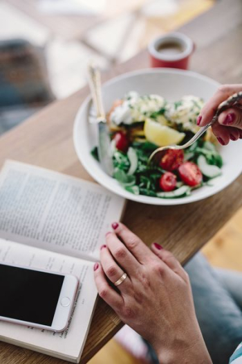 Woman eating breakfast and reading a book Woman eating breakfast and reading a book