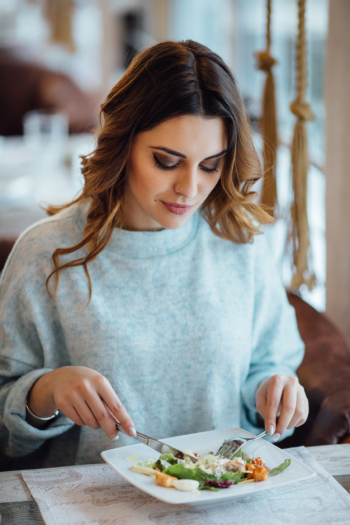 Woman eating Caesar salad in restaurant Woman eating Caesar salad in restaurant
