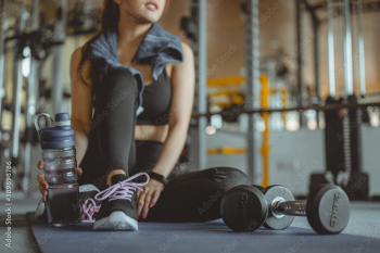 Woman exercise workout in gym fitness breaking relax after training sport with dumbbell and holdingbottles healthy lifestyle, Athlete Fitness ,workout, gym exercise,lifestyle and healthy concept.