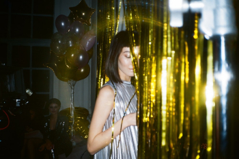 Woman Hiding Behind Gold Foil Curtain Woman Hiding Behind Gold Foil Curtain
