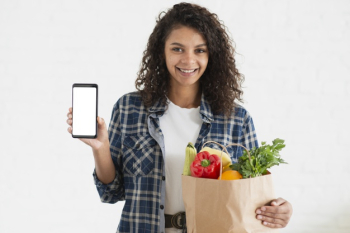 Woman holding a vegetables bag and a phone mock up Free Photo