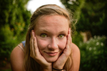 woman holds face near grasses woman holds face near grasses