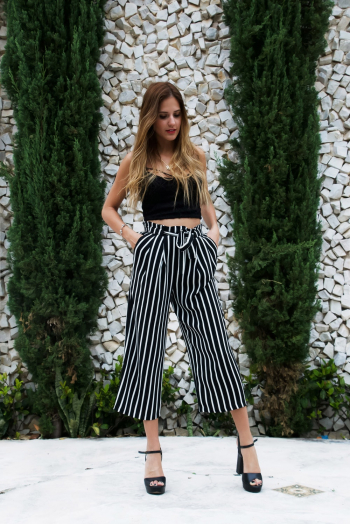 Woman in Black Crop Top Standing Near Arbor Vitae