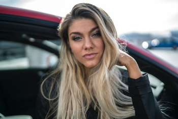 woman in black jacket standing beside red car