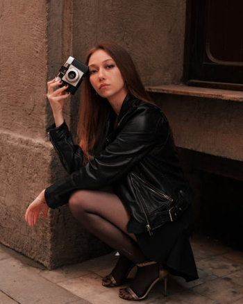 Woman in Black Leather Jacket Sitting on Brown Concrete Stairs · Free Stock Photo