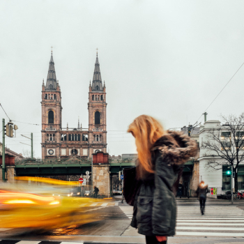 Woman in Black Parka Jacket Near Brown Cathedral