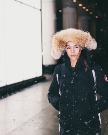 woman in black parka jacket standing while snowing woman in black parka jacket standing while snowing