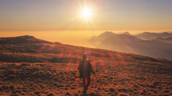 woman in blue jacket walking on desert during sunset woman in blue jacket walking on desert during sunset
