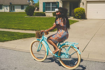 woman in brown and blue dress riding blue bicycle woman in brown and blue dress riding blue bicycle