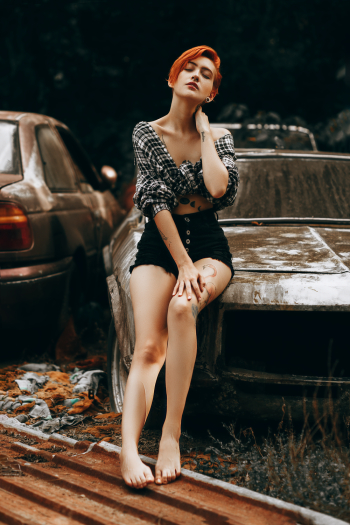 Woman in Crop Top and Black Short-shorts Sitting on Wrecked Car Woman in Crop Top and Black Short-shorts Sitting on Wrecked Car