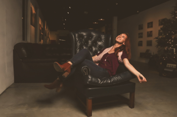 Woman in Maroon Scoop-neck Shirt Sitting on Black Leather Sofa Chair