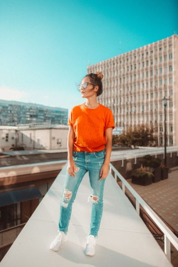 woman in orange crew-neck top standing footbridge woman in orange crew-neck top standing footbridge