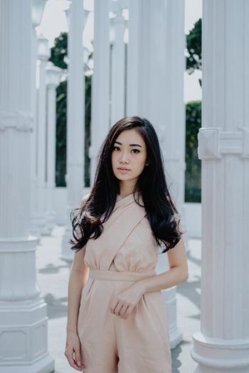 woman in peach-colored dress standing near pillars