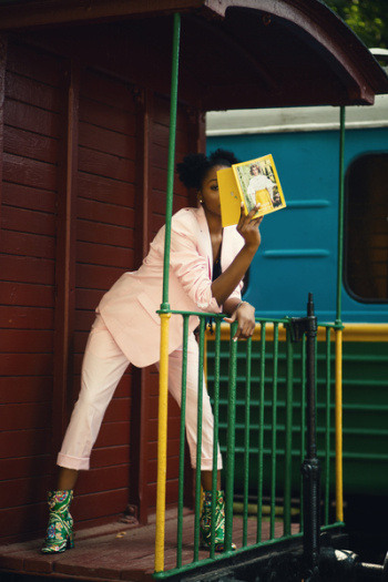 Woman in Pink Suit Coat Leaning on Green Steel Fence Woman in Pink Suit Coat Leaning on Green Steel Fence