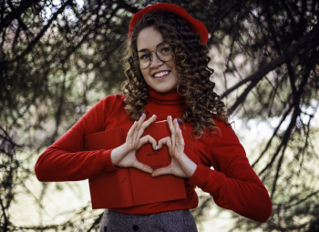 Woman in Read Long-sleeved Top Making Heart Shape Using Her Hands