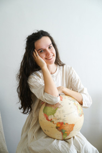 Woman in White Dress Holding Globe