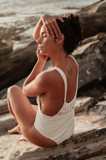 Woman in White One-piece Swimsuit Sitting on Rock