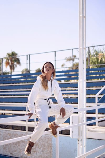 woman in white pullover hoodie and pants sitting on handrail during daytime