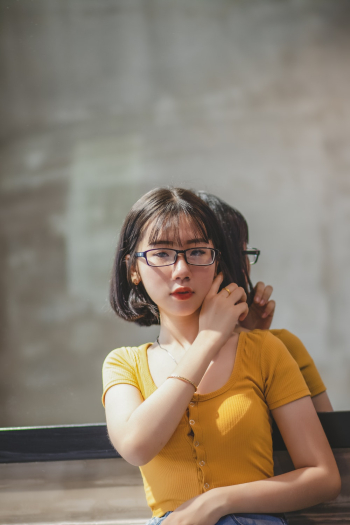 Woman in Yellow Scoop Neck Shirt and Black Framed Eyeglasses Standing in Front of Wall Mirror