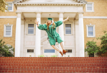 Woman jumping above stairs wearing graduation gown and a hat Woman jumping above stairs wearing graduation gown and a hat