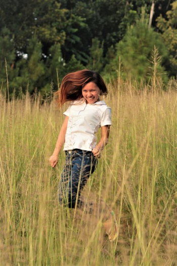 Woman Jumping Between Grass